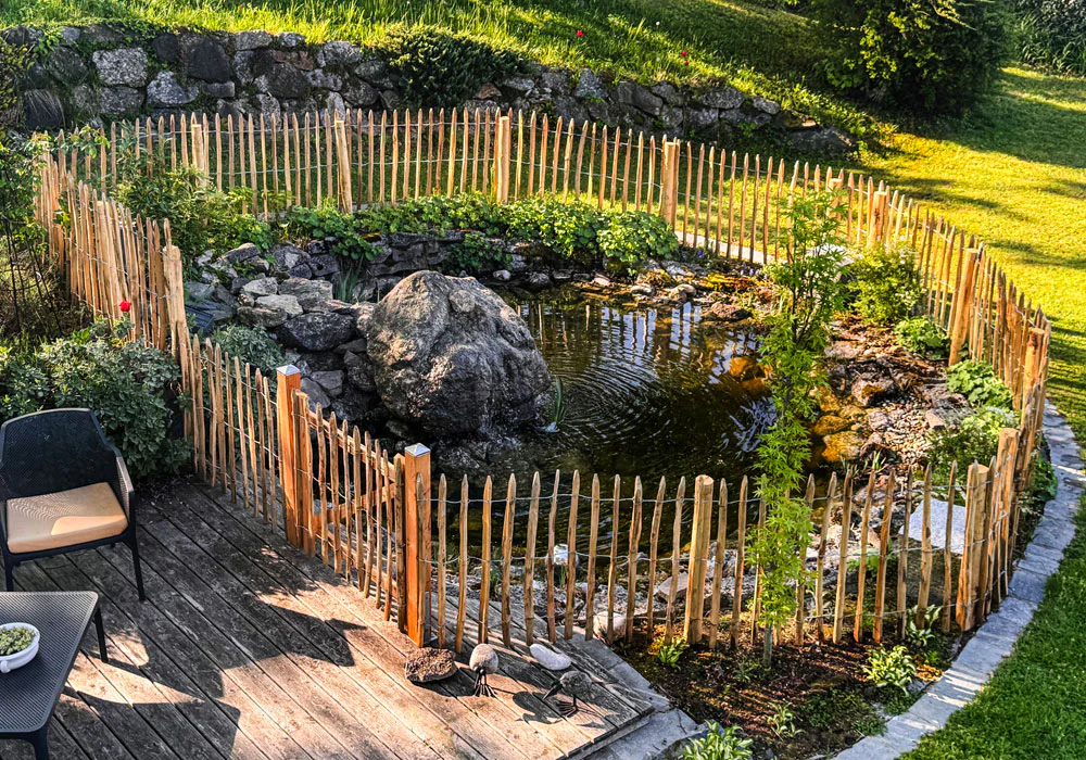 Staketenzaun mit Tür als Teichumrandung